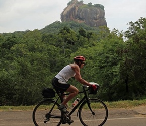 Carel Foster cycles past Sigiriya Rock Fortress