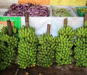 Bunches of green bananas outside a shop