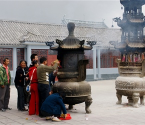 Putting prayer papers into the burner on Jade Mountain